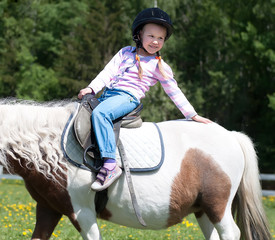 Cute little girl riding a horse pony