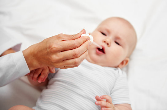 Portrait Of Baby Girl Getting Vaccine Drops In Clinic. Health Care And Therapy Concept.