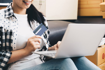 Shopaholic, Young woman holding credit card and using laptop computer at home. Online shopping concept