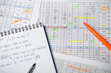 Financial tables on paper and a notebook with calculations