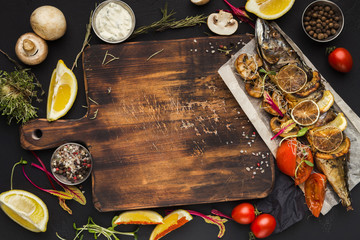 Grilled fish, cooking ingredients on wooden cutting board, top view