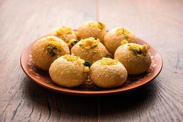 Stuffed Sev Puri is a popular Indian roadside chat item, served in a white plate. Top view, selective focus