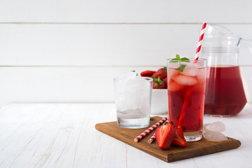 Homemade delicious strawberry compote in glass jar on white wooden table