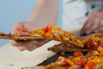 family is very fond of pizza. the hands of children and adults over homemade pizza made by own hands, on a stone dish and white table of boards