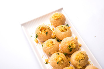 Stuffed Sev Puri is a popular Indian roadside chat item, served in a white plate. Top view, selective focus