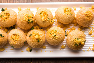 Stuffed Sev Puri is a popular Indian roadside chat item, served in a white plate. Top view, selective focus