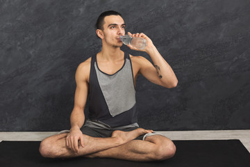 Fitness man drinking water at gym