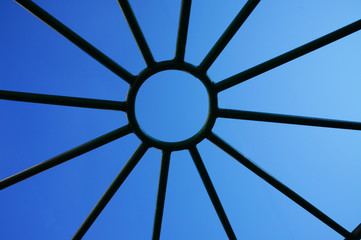 metal lattice in the form of the sun against the background of the blue sky