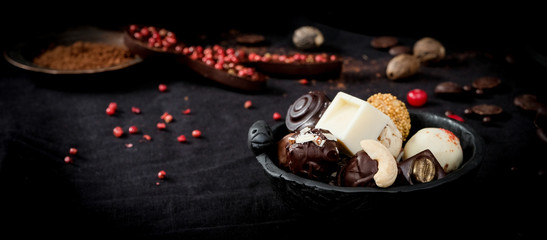 Obraz na płótnie Canvas A variety of truffles in a black clay pile and chocolate spoon with red pepper