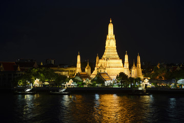 Fototapeta premium Świątynia Wat Arun w nocy z brokatowym światłem na wodzie