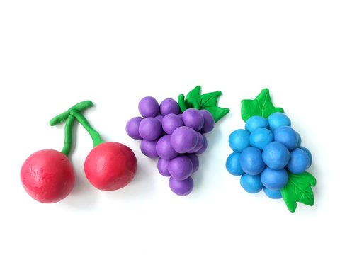 Colorful clay plasticine made are variety fruits on white background, delicious red cherry grapes blueberry dough 