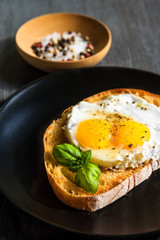 French sandwich with fried egg with two yolks on a black plate