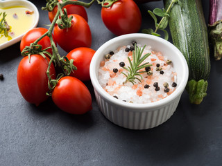Mix of raw vegetables with salt, spices on dark background. Clean healthy eating concept