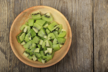 slices of kiwi in wooden plate isolated on wooden background. top view
