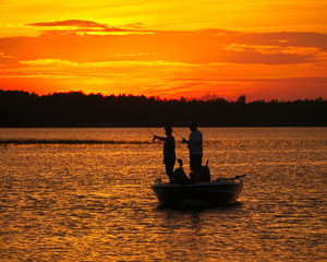 Silhouette of men fishing in a boat on a lake just after sunset in Bemidji Minnesota.