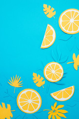 Lemon slices and tropical leaves pattern on a bright blue background. Papercraft flat lay header.
