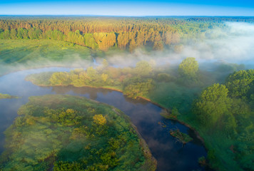 Fototapeta na wymiar Sunny summer morning on river. Fog over meadow. Summer nature. Amazing landscape aerial view.