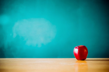 Apple on the desk in front of blackboard