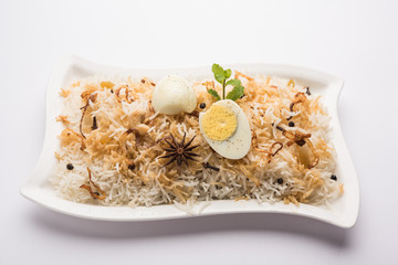 Egg Biryani - Basmati rice cooked with masala roasted eggs and spices and served with yogurt, selective focus
