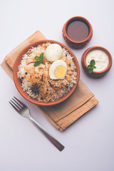 Egg Biryani - Basmati rice cooked with masala roasted eggs and spices and served with yogurt, selective focus