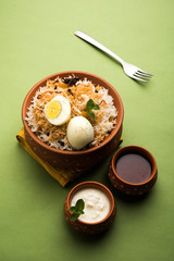 Egg Biryani - Basmati rice cooked with masala roasted eggs and spices and served with yogurt, selective focus
