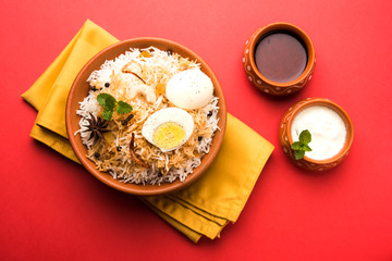 Egg Biryani - Basmati rice cooked with masala roasted eggs and spices and served with yogurt, selective focus