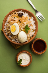 Egg Biryani - Basmati rice cooked with masala roasted eggs and spices and served with yogurt, selective focus