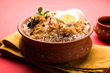 Egg Biryani - Basmati rice cooked with masala roasted eggs and spices and served with yogurt, selective focus