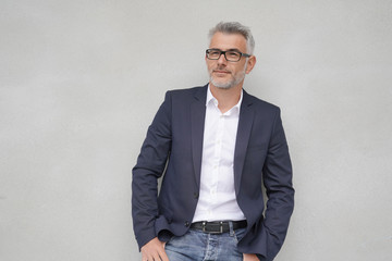 Businessman leaning on concrete wall, isolated