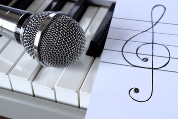 Synthesizer, microphone and treble clef on white paper