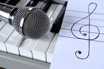 Synthesizer, microphone and treble clef on white paper