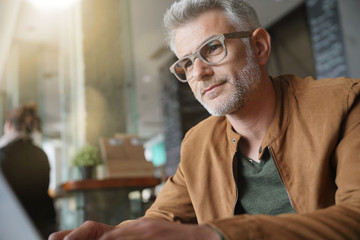 Man in trendy coffee shop working on laptop computer