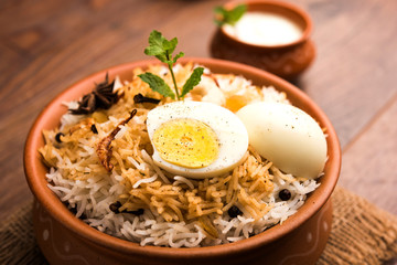 Egg Biryani - Basmati rice cooked with masala roasted eggs and spices and served with yogurt, selective focus