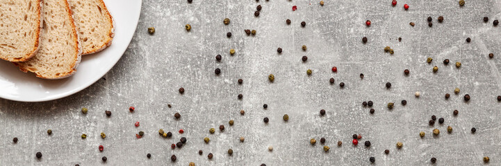 Panoramic view on fresh bread on the white plate and colorful pepper on the concrete kitchen table