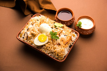 Egg Biryani - Basmati rice cooked with masala roasted eggs and spices and served with yogurt, selective focus