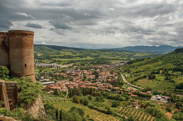 Obraz premium Overview of stone tower, green hills, vineyards and town rooftops near a road. From the city center of Orvieto, an ancient, pleasant and well preserved medieval town. Located in Umbria, central Italy