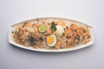 Egg Biryani - Basmati rice cooked with masala roasted eggs and spices and served with yogurt, selective focus