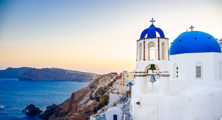 Fototapeta na wymiar Oia town on Santorini island, Greece. Traditional and famous houses and churches with blue domes over the Caldera, Aegean sea at sunny day
