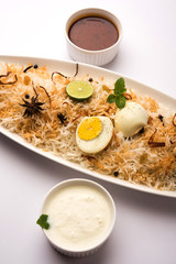 Egg Biryani - Basmati rice cooked with masala roasted eggs and spices and served with yogurt, selective focus