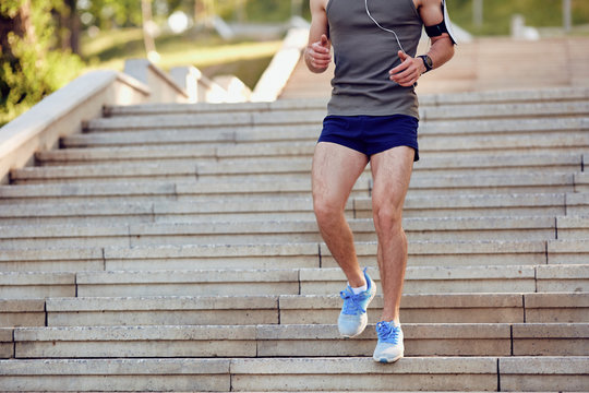 A Young Male Runner Runs Down The Steps In The Park In The Summer.