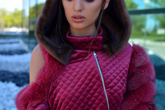 chica joven con expresi&oacute;n de preocupaci&oacute;n o duda vistiendo una chaqueta de piel roja con capucha de vis&oacute;n