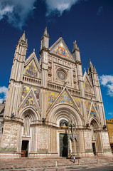 Fototapeta na wymiar Facade view of the opulent and monumental Orvieto Cathedral (Duomo) under sunny blue sky in Orvieto, a pleasant and well preserved medieval town. Located in Umbria, central Italy