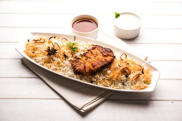 Authentic Fish Biryani served in a white plate over white background, selective focus