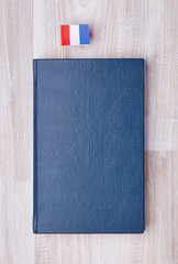 Flat lay of blue textured notepad with French flag on toothpick as bookmark.