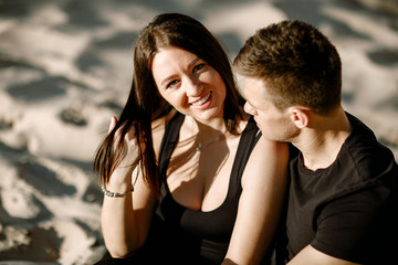 The brunette looks at the camera and smiles. A date on the beach.
