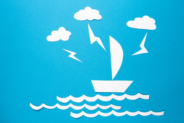 Lightning strikes in paper ship origami floats on waves. Clouds and lightning over white paper ship with sail on blue background. concept of obstacles and disasters. Threat and danger.