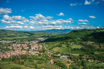 Fototapeta na wymiar Overview green hills, vineyards and town rooftops near a road. From the city center of Orvieto, an ancient, pleasant and well preserved medieval town. Located in Umbria, central Italy