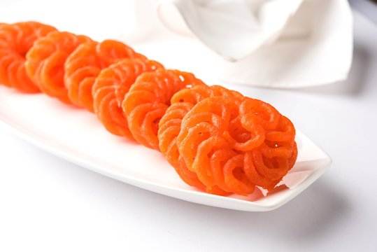 Indian sweet Imarti or Jalebi served in white ceramic plate over white background