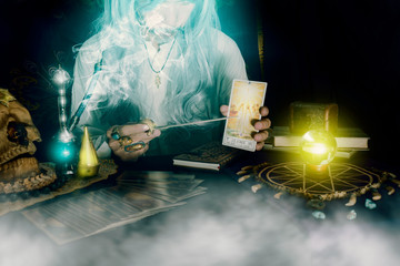 View of old fortune teller with tarot cards in the room at night. Dark tone.