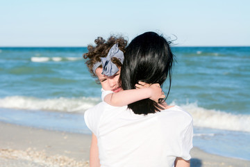 Fototapeta na wymiar mom and doughter on the beach, hugging together